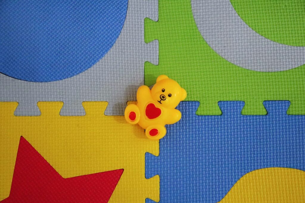 a yellow teddy bear sitting on top of a puzzle